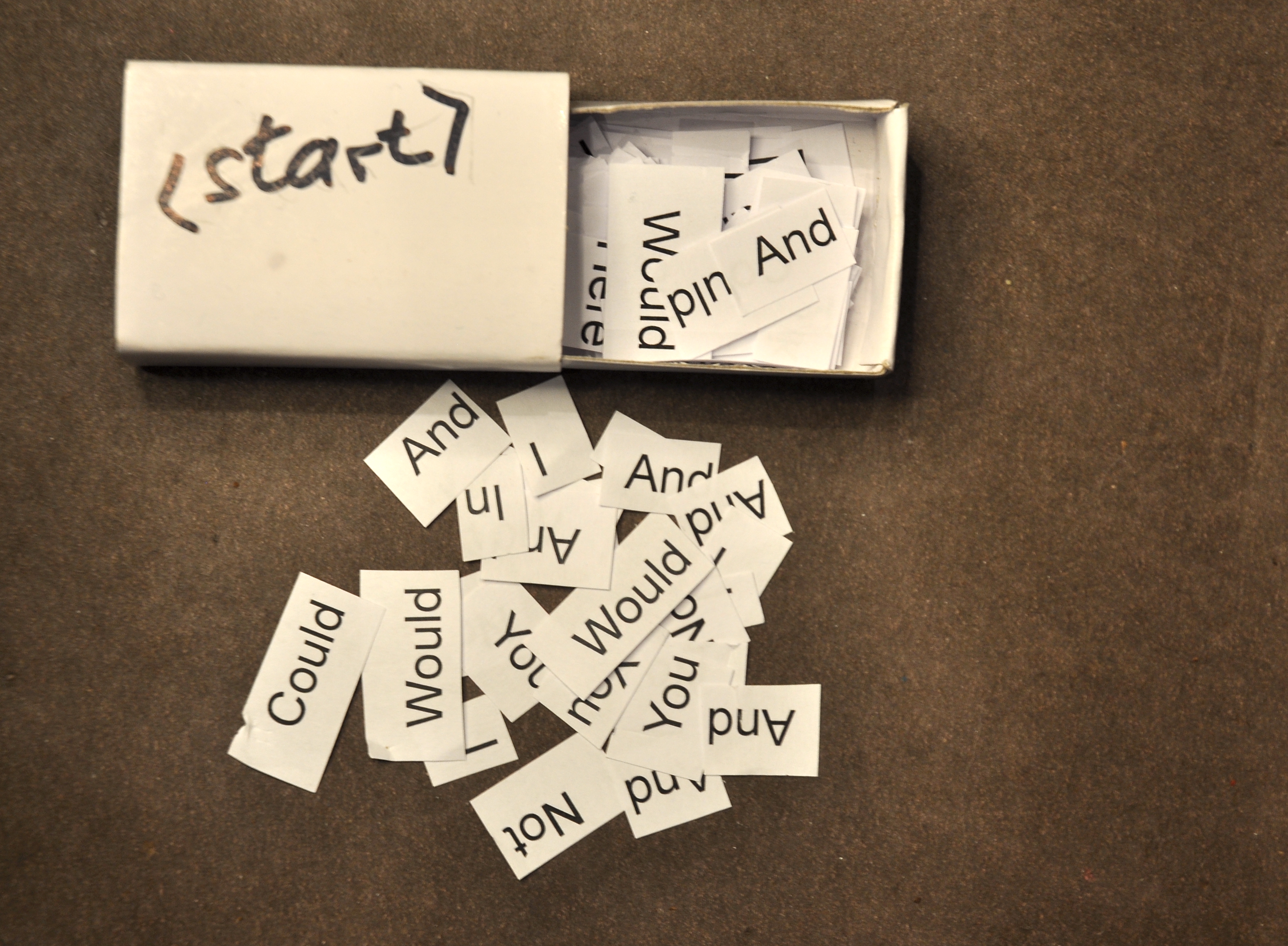 a matchbox with the word 'start' written on top, open to show many words on slips of paper